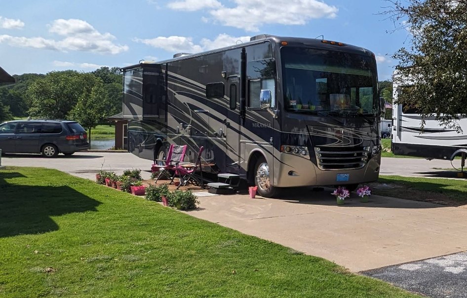 A Class-A motorhome on a concrete pad with a pond view