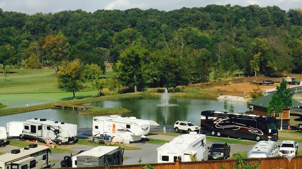 Elevated view across the RV sites, the spring-fed pond and fountain, and the wooded Osage Valley at The Creeks